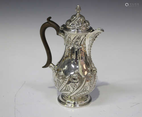 A late Victorian silver coffee pot of baluster form, embossed with scrolling foliage, London 1899 by
