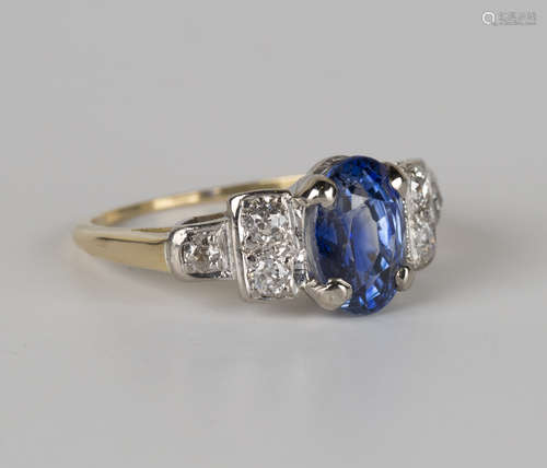 A gold, sapphire and diamond ring, claw set with an oval cut sapphire between circular cut diamond