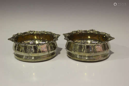 A pair of George IV silver circular wine coasters, each rim cast with stylized leaves and scrolls