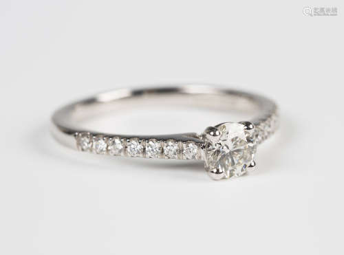 An 18ct white gold and diamond ring, claw set with the principal circular cut diamond between