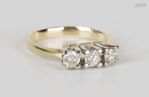 A gold and diamond three stone ring, claw set with a row of circular cut diamonds, detailed '585',