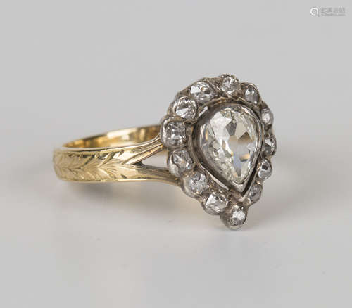 A gold and diamond ring, claw set with a pear shaped diamond within a surround of rose cut