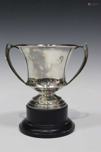 A George V silver trophy cup, the urn shaped body flanked by two angular handles, on a stepped foot,