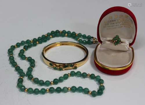 A gold, jade and diamond oval hinged bangle, the front with an applied spray motif, on a snap clasp,