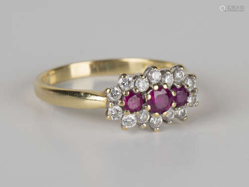 An 18ct gold, ruby and diamond ring, mounted with three circular cut rubies within a surround of