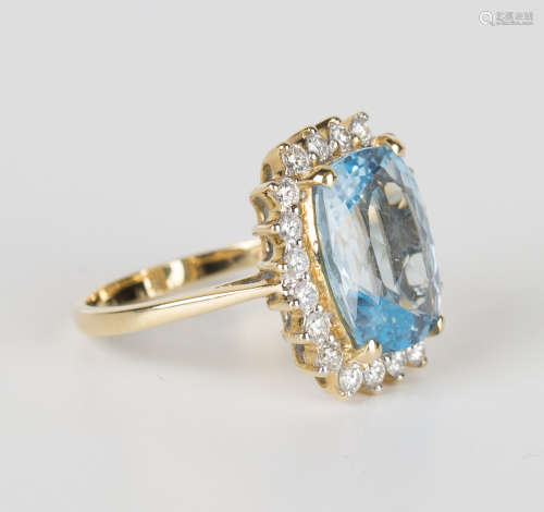 An 18ct gold, blue topaz and diamond ring, claw set with an oval cut blue topaz within a surround of