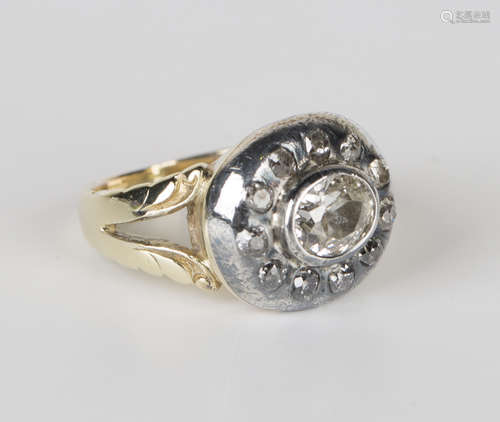 A gold and diamond ring, collet set with an oval cut diamond within a surround of eleven circular