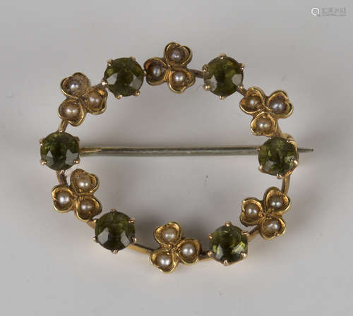 A gold, seed pearl and peridot oval brooch, circa 1910, claw set with six circular cut peridots