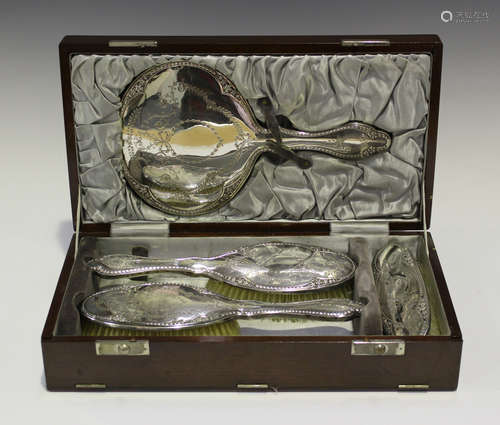 A George V silver four-piece dressing table set, engraved with tied ribbon bows amongst foliate