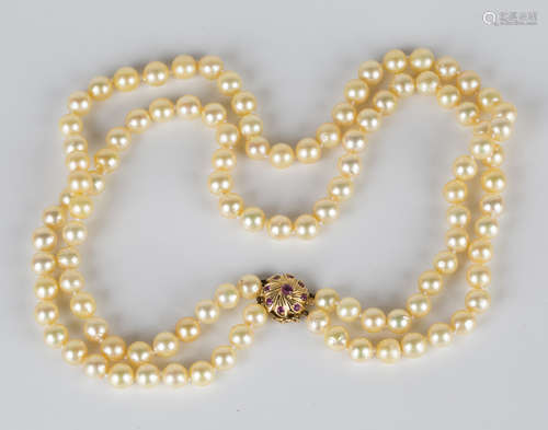 A two row necklace of slightly graduated cultured pearls on a gold and ruby clasp with spiral