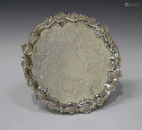 A Victorian silver circular salver with engraved centre and cast scroll rim, on three scroll feet,