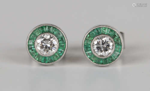 A pair of white gold, diamond and emerald circular cluster earrings, each collet set with a circular