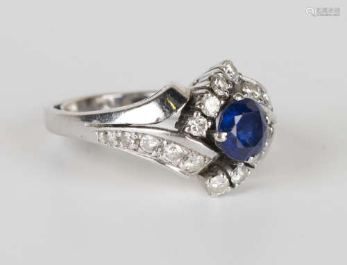 A white gold, sapphire and diamond ring in a twist design, claw set with a circular cut sapphire