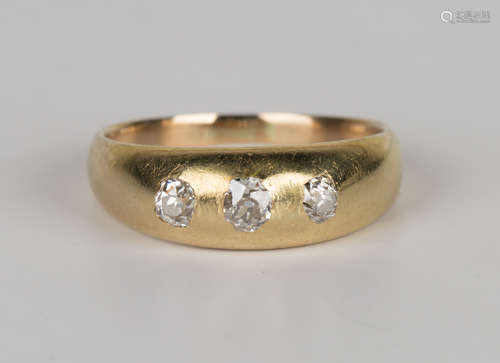 A gold and diamond three stone ring, gypsy set with a row of cushion cut diamonds, ring size