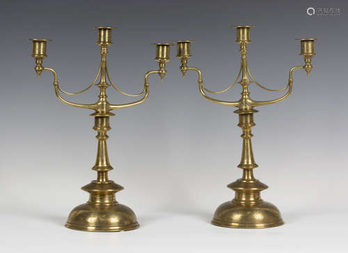 A pair of late 19th century Arts and Crafts brass three-light candelabra, the scrollwork branches