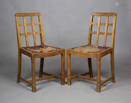 A pair of early 20th century oak lattice back dining chairs, probably by Heals, raised on