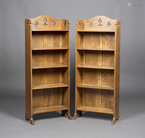 A pair of Edwardian Arts and Crafts oak five-tier open bookcases, probably by Liberty & Co, the