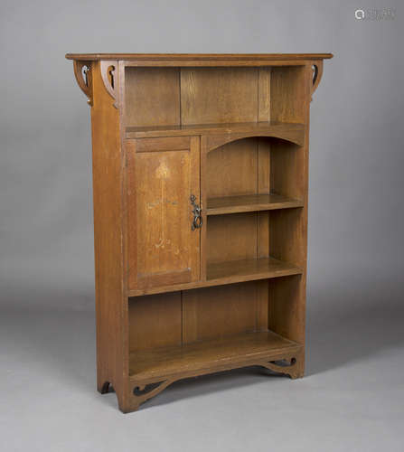 An Edwardian Arts and Crafts oak open bookcase, the moulded top above pierced bracket supports,