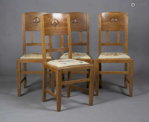 A set of four Edwardian Arts and Crafts oak framed and ash backed dining chairs, designed by W.J.