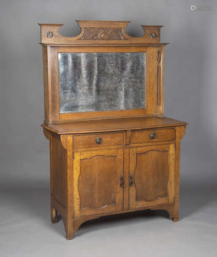 An Edwardian Arts and Crafts oak sideboard, the mirror back with pierced side supports and carved