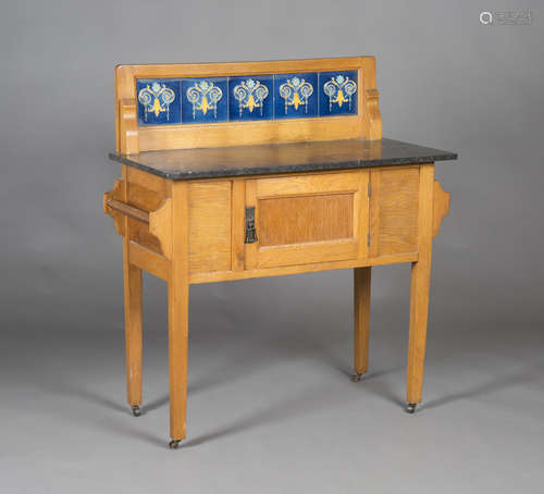 An Edwardian Arts and Crafts style oak washstand, the back inset with blue glazed tiles above a