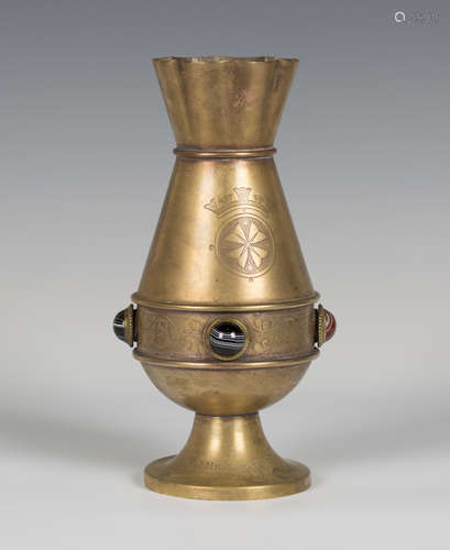 A late Victorian Gothic Revival brass vase by Jones & Willis, the shaped rim above a flared body and