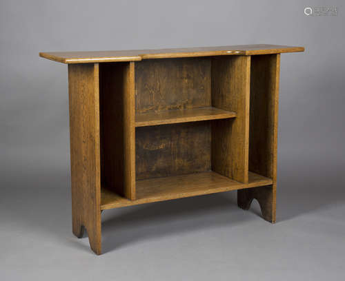 An early 20th century Arts and Crafts style oak open bookcase, the inverted breakfront top above