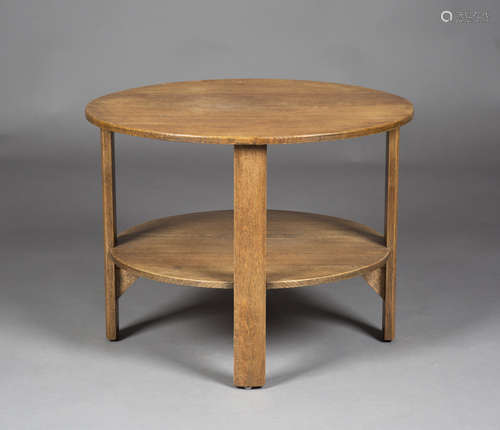 An early 20th century oak circular two-tier occasional table, in the manner of Heals, raised on