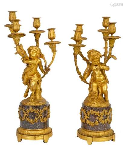 Pair of large Louis XVI style candelabra in red porphyry and chased and gilded bronze showing a young satyr or a little girl with grapes in the round, each holding four arms of light in the shape of a leafybranch According to models by Clodion French work, early 19thcentury period H: 54 and 56 cmProvenance: Château de la Roquette (Hainaut)(accidents and restorations) A document signed by François d'Ansembourg on 8 June 1991is attached.