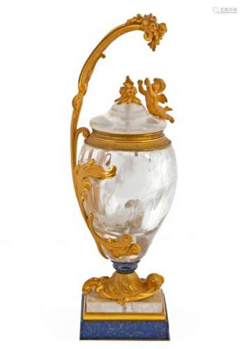 One-handled vase and its lid of Louis XV inspiration in cut rock crystal, chased and gilded bronze and Afghan lapis lazuli Lid decorated with a cherub in a roundbump French work, second half 19thC: +/- 39,5 cmProvenance: Château de la Roquette (Hainaut) An insurance expertise signed by Marcel Berkovitch on December 20, 1992is attached.