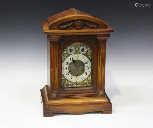 An early 20th century walnut mantel clock with eight day movement chiming on gongs, the backplate