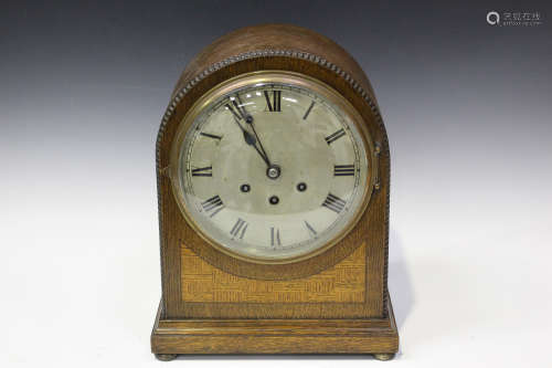 A George V oak mantel clock with eight day movement chiming on gongs, the backplate with Gustav