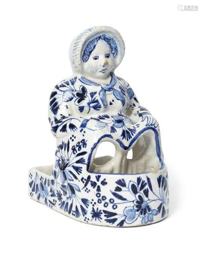 A tin glazed blue and white earthenware figure of a lady, 19th century, modelled seated in a bath,