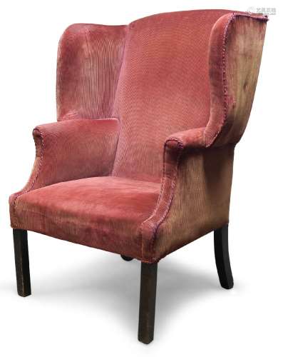 A George III wingback armchair, with serpentine wings, upholstered in red velvet, raised on square