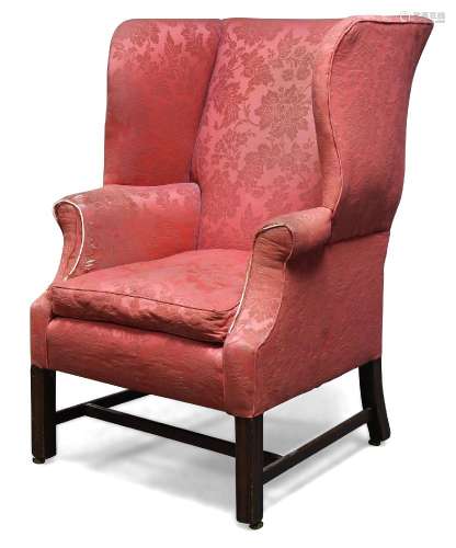 A George III wingback armchair, with serpentine wings, upholstered in red floral pattern fabric,