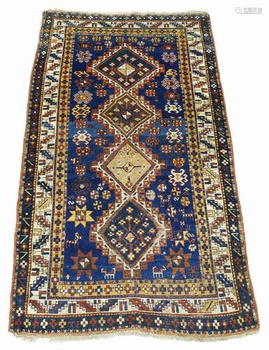 A Kazak rug, mid 20th Century, with four lozenge medallions in deep blue field, with ivory main