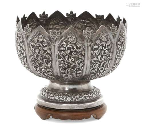 An Indian silver bowl, raised on a wooden stand to a circular foot, the body chased with elaborate