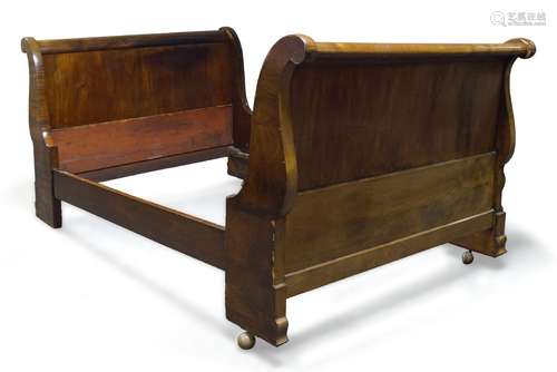 A Charles X mahogany lit en bateau, with scroll end headboard and footboard, raised on later