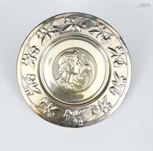 An electroplated metal charger, the well decorated with a portrait of a young male classical