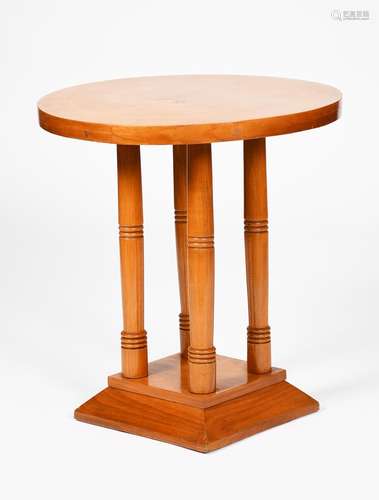 A beech laminate side table, circular top on four turned, cylindrical columns and flaring square