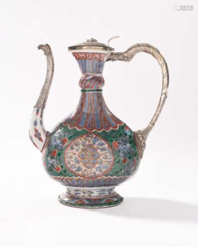 China Large baluster-shaped porcelain ewer for the Ottoman market with polychrome decoration of the enamels of the Green Family of flowers in storerooms on a pebbled and flowery green background and on the neck and base of simulated gadroons in red and gold on a blue background Ming Dynasty, 17th century.  H. 30 cm.  Accidents and restorations. The lid, the handle and the spillway in modern silver.