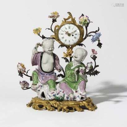 Clock in gilded bronze and Chinese porcelain with a decoration of two children in a porcelain flower surround, resting on a base decorated with foliage, (restorations, especially gilding and movement).  Louis XV period.  H : 30 cm, W : 24 cm