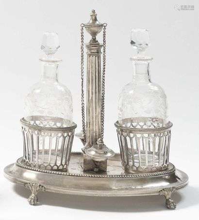 Silver oval oyster frame, resting on four claw feet, openwork supports, the corks held by chains with a central fluted barrel topped by an urn. PARIS 1789 Master goldsmith : Noël NEUSECOURT or NESECOUR received in 1783, quai des orfèvres Weight : 820 g (Missing the nuts to fix the cruets supports to the tray, slight indentations on the bottom)
