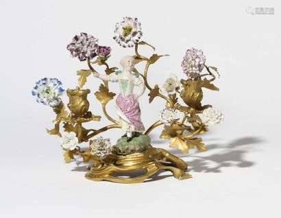 Candelabrum in gilt bronze and Höchst porcelain depicting a young girl with two arms of light, porcelain flowers and foliage decoration. (Restorations, especially gilding) Louis XV period. H: 21.5 cm, W: 28 cm