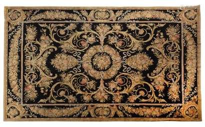 Exceptional and important Savônnerie style rug. Carpet made and knotted by hand in the Savônnerie style, wool velvet on cotton foundations. Black field decorated with fine golden floral branches crenellated in twists and scrolls framing a central medallion with a crown of flowers inlaid with a polychrome floral bouquet decorated with double floral baskets and horns of plenty with floral sprays. Main border recalling the central field. 20th century 550 x 365 cm (Good condition)