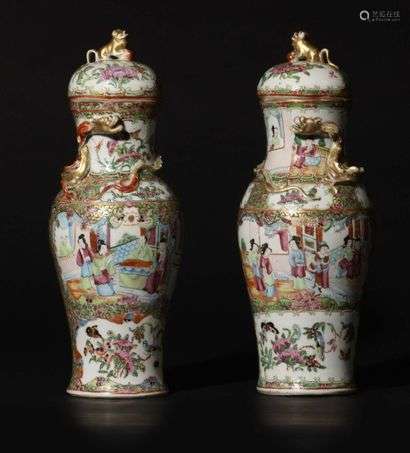 Canton Pair of baluster-shaped covered porcelain vases with polychrome decoration of Rose Family enamels of animated palace scenes, birds, butterflies and flowering branches in reserves surrounded by flowering foliage on a gold background, the neck decorated with a dragon in relief, the grip of the lid in the shape of a Fô dog. 19th century.  Height 33 cm.