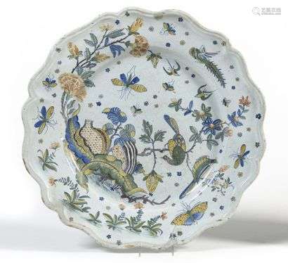 Rouen (kind of) Large round earthenware dish with contoured rim with polychrome decoration of pomegranates, phoenixes, birds, butterflies and flowering shrubs. 19th century. D. 46,5 cm. A small chip.