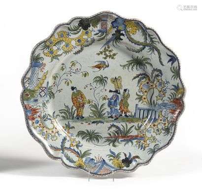 Rouen (kind of) Large round earthenware dish with contoured edge with polychrome decoration of three Chinese on a terrace and rocks pierced on the edge. 19th century. D. 47 cm.
