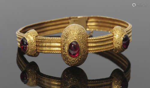 High grade yellow metal and garnet set bracelet, a design with three engraved oval shaped domes,