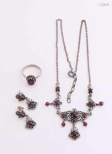 Three silver jewelry with garnet. A ring with oval grenade in a bead edge, a choker with floral-